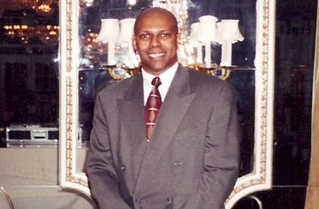 A man wearing a grey suit smiling at camera