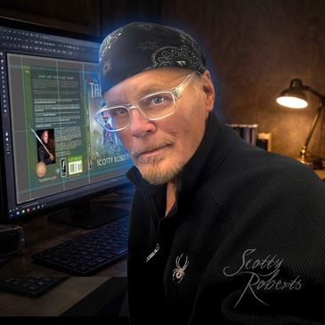 Man wearing glasses and a bandana working at a computer with book cover design.