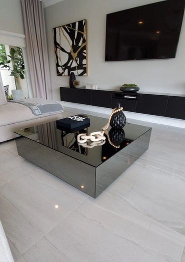Modern living room with a reflective black coffee table and minimalist decor.