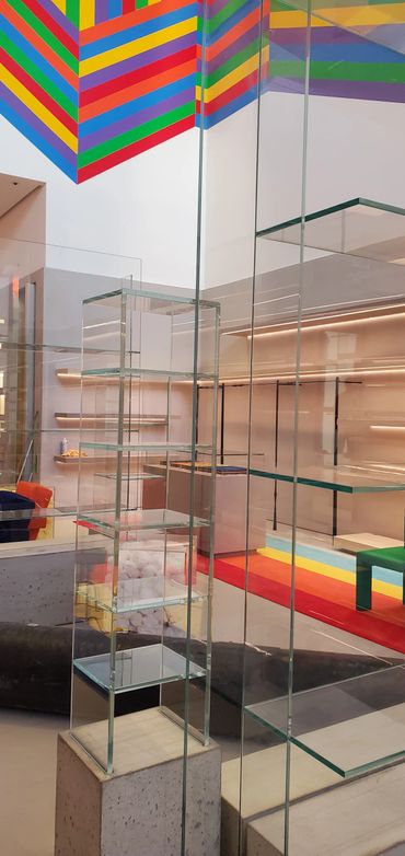 Colorful striped ceiling and modern glass shelves in a minimalist interior.