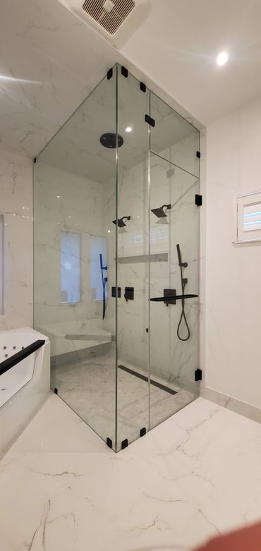 Modern bathroom with glass shower enclosure and marble tiles.