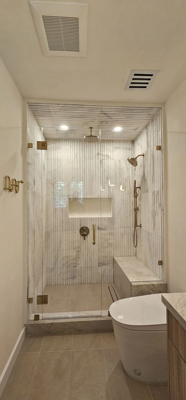 Modern bathroom with marble shower and glass door.