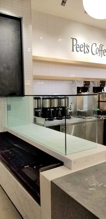 Empty Peet's Coffee counter with brewing equipment and glass divider.