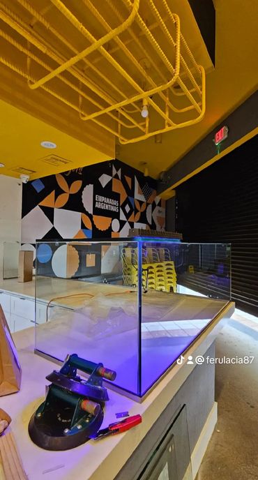 Modern empanada shop interior with bright yellow ceiling and geometric wall art.