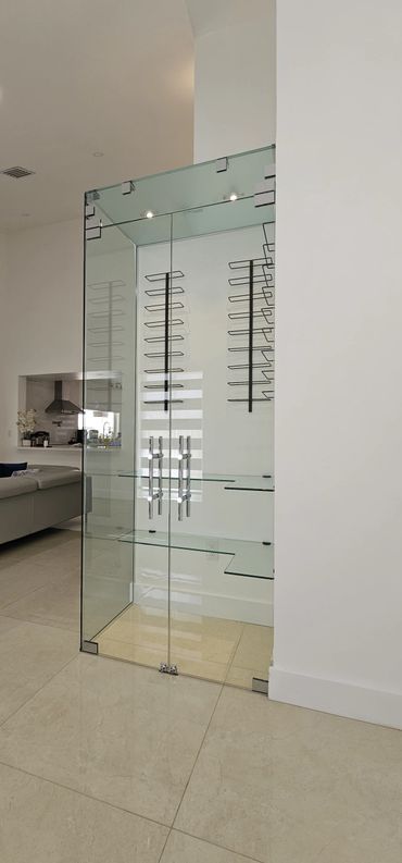 Modern glass wine cellar with metal racks inside a stylish living space.