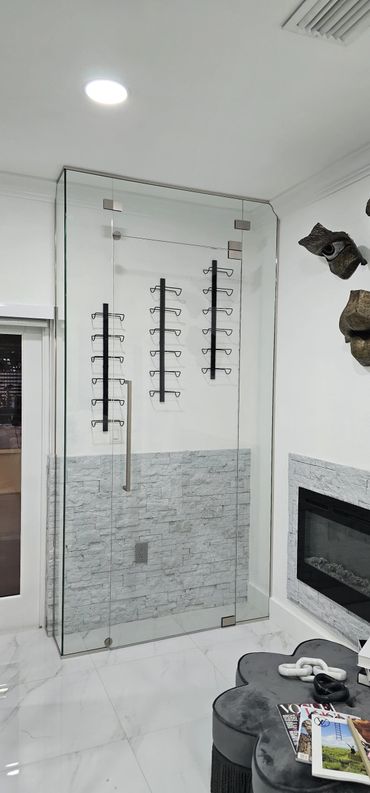 Modern glass enclosure with black wall racks and stone accents in a sleek living space.