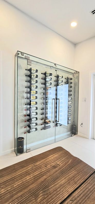 Modern glass wine storage with bottles displayed horizontally on a wall rack.