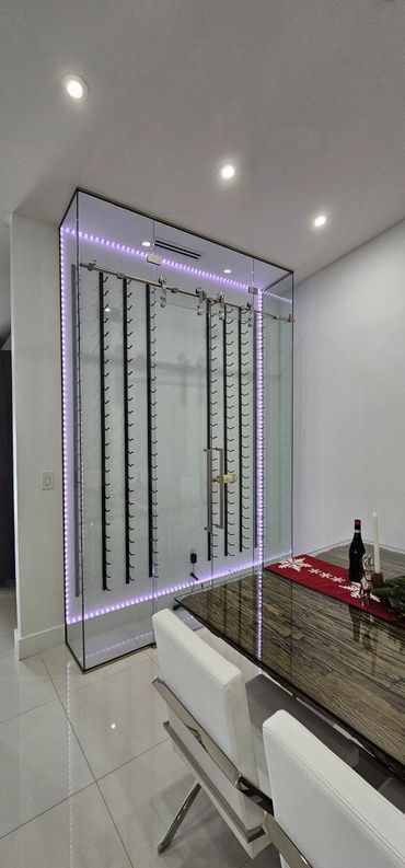 Modern glass wine rack with purple LED lighting in a sleek dining area.