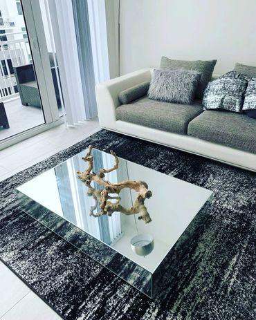 Modern living room with mirrored coffee table and textured sofa cushions.