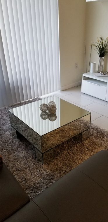 Modern living room with mirrored coffee table and decorative spheres.