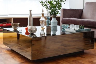 A modern mirrored coffee table with decorative vases and books.