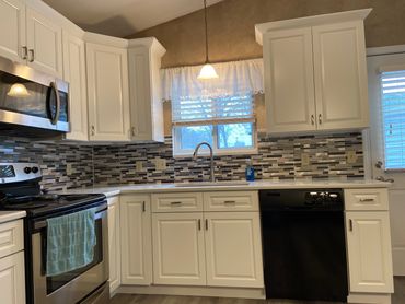 Remodeled kitchen with white soft-close cabinets, crown molding, and newly installed backsplash.