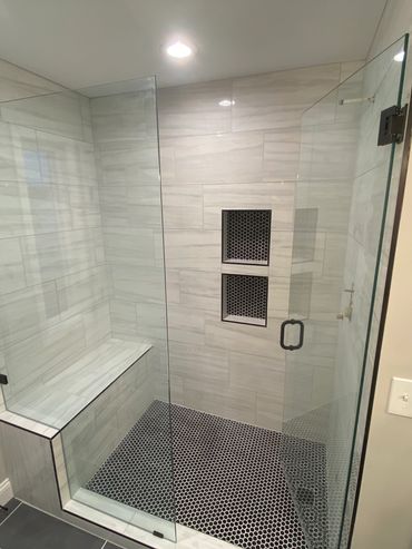 Walk-in shower with full bench, custom shower niches, frameless glass, and hexagon mosaic tile.