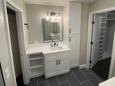 Master bathroom with walk in closet, his and her sinks, linen tower cabinet, and quartz countertops.