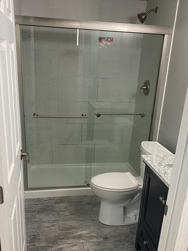 Finished basement bathroom with vinyl plank flooring, full shower, and new vanity.