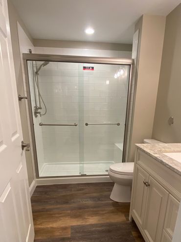 Bathroom with vinyl plank wood flooring, walk in shower with subway tiles.