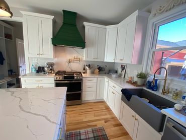 Farmhouse kitchen with shaker cabinets, gold kitchen cabinet hardware, and farmhouse sink.
