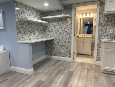 Finished basement wet bar with full bathroom, floating shelves, and vinyl plank flooring.