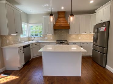 Eitchen with white shaker cabinets and crown, custom range hood, backsplash & quartz countertops.