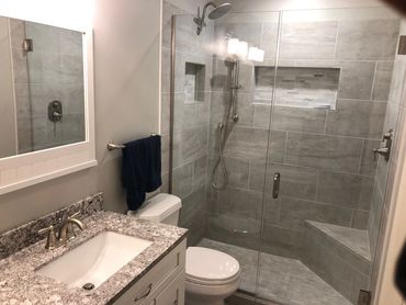 Remodeled bathroom with white shaker vanity, granite countertops, and ceramic tile.