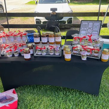 A table with homemade jams and preserves displayed for sale outdoors.