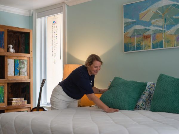 smiling working making the bed at Airbnb