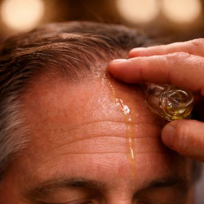 A man pouring oil on his forehead.