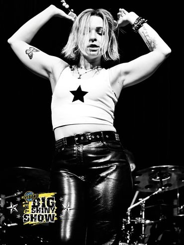 Energetic female singer performing passionately on stage in black and white.