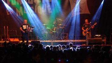 Live band performing on stage with colorful lights and an engaged crowd.