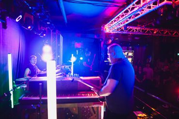 Live band performing on stage with vibrant neon lights and an engaged audience.