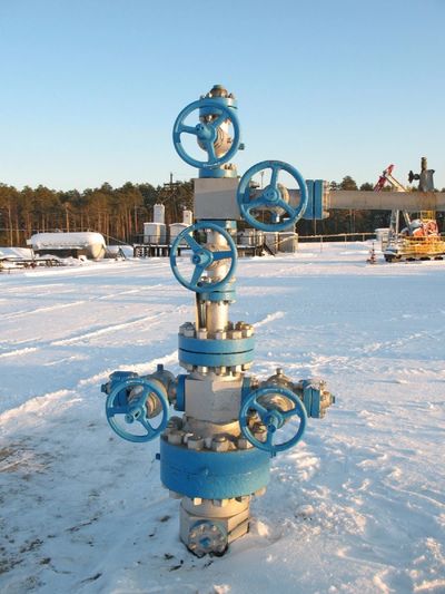 Blue industrial valve assembly in a snowy outdoor setting.