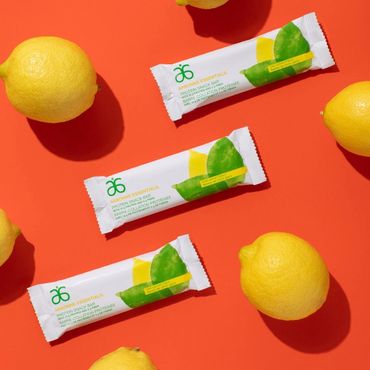 3 Arbonne chocolate protein bars on a coral table with lemons to decorate.