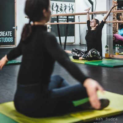 Professional yoga teacher with her students teaching practice waking up the body.