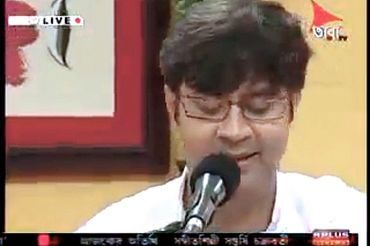 A man speaking into a microphone on a live TV broadcast.