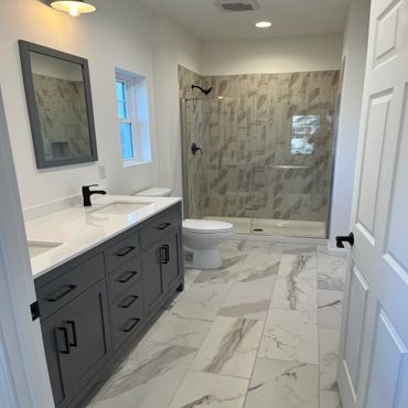 Modern bathroom with gray cabinetry and marble tiles.