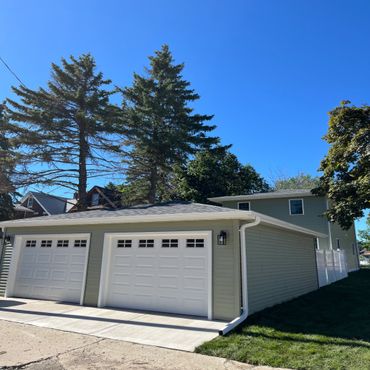 Modern double garage with white doors under a clear blue sky.