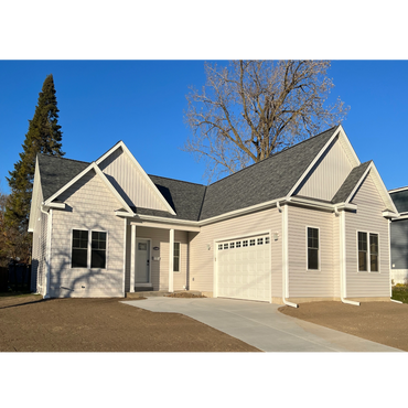 Newly built single-story house with a clean driveway and clear blue sky.