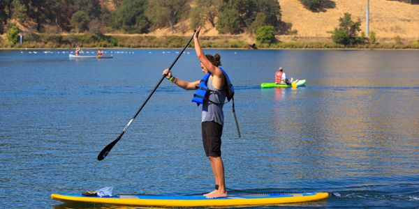 A person riding a blue and yellow paddle board