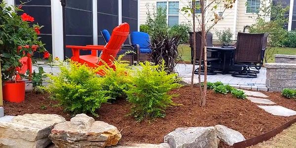 Plant design with paver patio and boulders, stepping stones and a seat wall