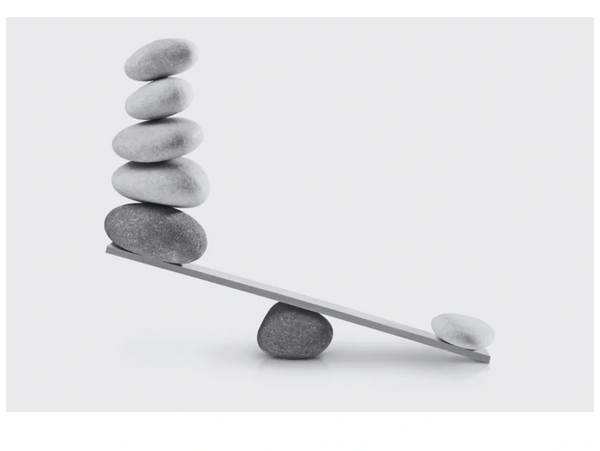 Balanced stones on a seesaw creating an imbalance.