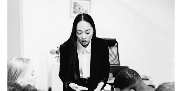 A woman leads a group meeting, explaining notes to attentive colleagues.