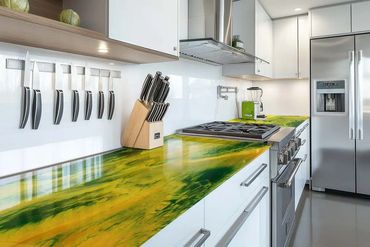 Modern kitchen with vibrant green and yellow marble countertops and stainless steel appliances.