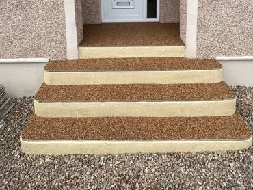 Neatly surfaced outdoor steps leading to a front door with gravel around them.
