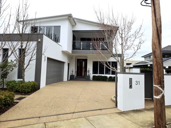 Modern two-story white house with balcony and garage.