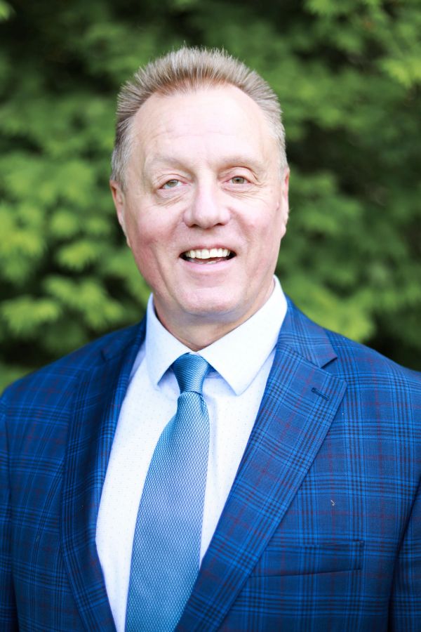 Smiling man in a blue plaid suit and tie outdoors.