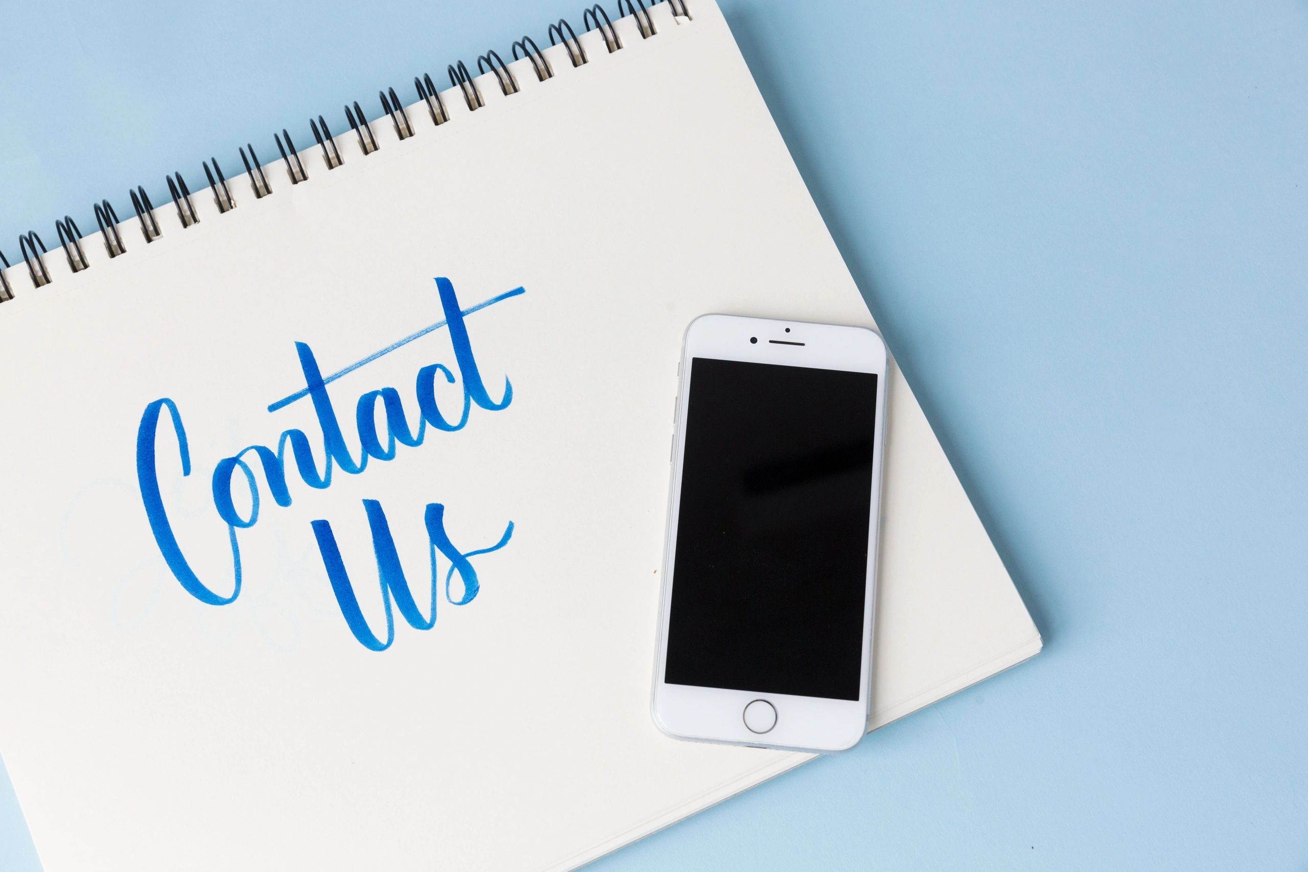 Contact Us with a phone on a notepad.