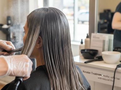Person getting a professional hair straightening treatment.