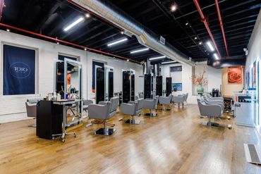 Empty modern hair salon with multiple styling chairs and mirrors.