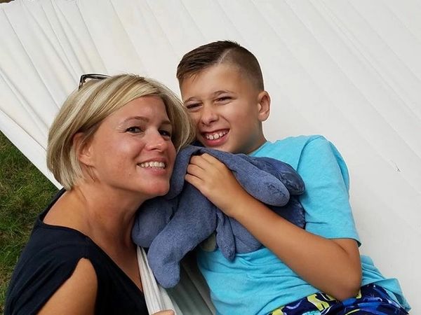 A smiling woman and boy holding a plush toy, sharing a happy moment.