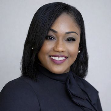 Professional woman smiling confidently in a black outfit with a bow.